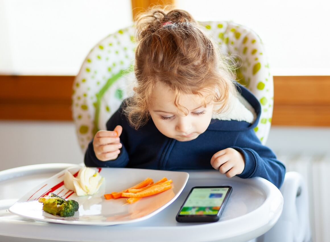 Dijete gleda mobitel tijekom hranjenja